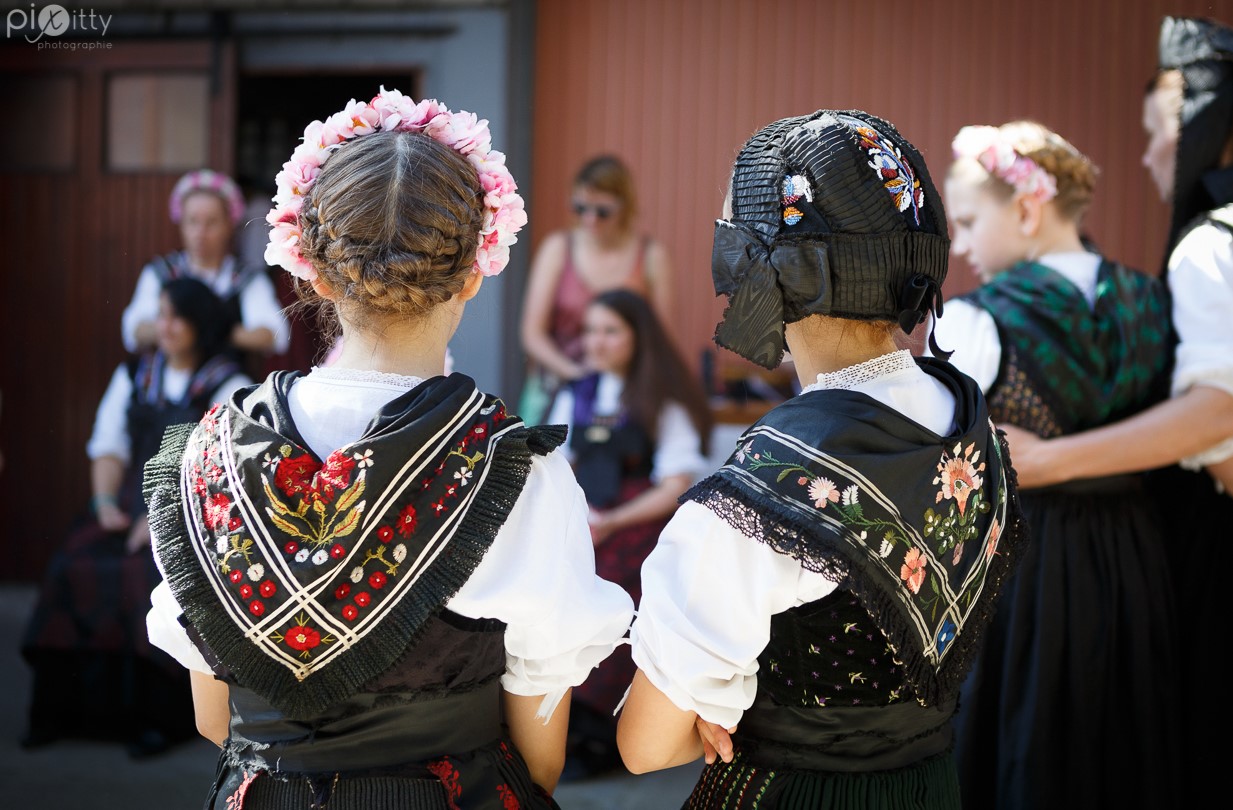Vue de dos sur les foulards d'époque, bonnets et couronnes de fleurs portées par les jeunes filles de Seebach